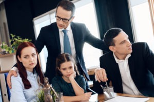 Lawyer calms family down with little girl who gets divorced. Family in office of family lawyer. Young man and beautiful woman decide who will be main guardian of little girl.