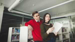 Two college students in a big modern library, reading books