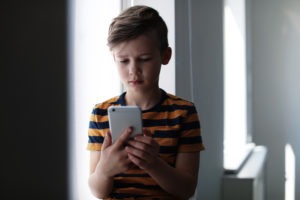 What Classifies Child Molestation as a Misdemeanor in California? | FAQ child using smartphone