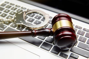 Los Angeles Child Pornography Lawyers | Simmrin Law A gavel rests with handcuffs on top of a laptop keyboard.