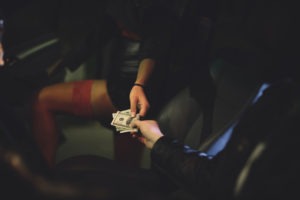 Los Angeles Prostitution Defense Attorneys | Simmrin Law | 24/7 Support A man hands money to a woman in his car.