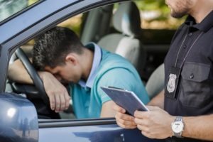Traffic Violation Lawyer in Tustin | Free Consultations 24/7 young motorist rests head on steering wheel while officer writes ticket