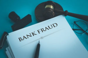 Los Angeles Bank Fraud Lawyers | Simmrin Law Group A gave, rubber stamp, glasses, and a stack of papers, top one reads “Bank Fraud”