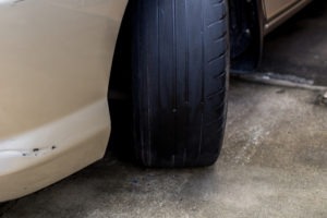 Bald Tire Code in California is §27465(b) | Simmrin Law Group Photo showing the bald front-right tire of a beige-colored car