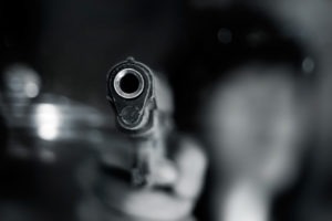 an assailant menacingly pointing a gun