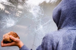 Person smashing a store window with a rock