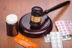 Moving Ecstasy Across City/ County Lines | Simmrin Law Group A judge’s gavel sits among illegal pills.