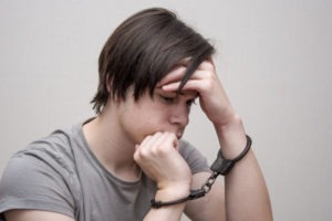 a teenager in handcuffs sitting alone