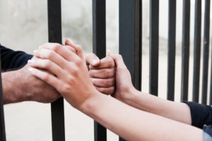 a woman holding the hands of a man as he grips bars from the other side