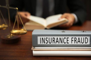 PC 548: Insurance Fraud by Damaging or Abandoning Property a binder labeled insurance fraud on the desk of a lawyer