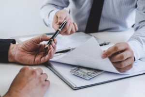 Bribery Lawyer in West Covina | Free Consultations 24/7 a businessman revealing a cash bribe in the middle of a contract