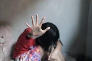 PC 288: Lewd and Lascivious Acts With a Minor Child Laws a young girl with her face buried in her knees and her hand out signing stop