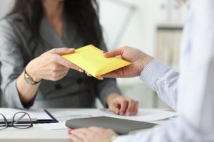 woman hands bulging envelope across table