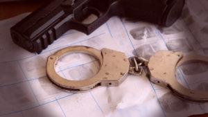 Weapons Charge Legal Services in Costa Mesa | Simmrin Law evidence gun next to fingerprints and handcuffs