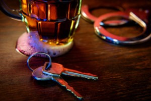 car keys mug of frothy beer and handcuffs on wooden bar