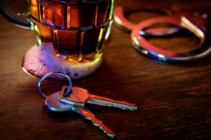 Santa Clarita DUI Attorney | Simmrin Law Group | 24/7 Help car keys mug of frothy beer and handcuffs on wooden bar