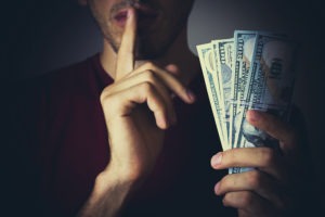 man whispering with money in his hand