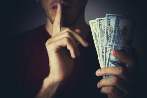 Embezzlement Lawyer in San Diego | Free Consults man whispering with money in his hand