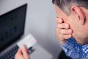 Identity Theft Lawyer in Irvine | Free Consultations 24/7 upset man holding a credit card by a laptop