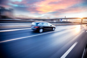 Black car driving on the freeway at sunset