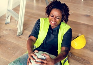 Workers' Compensation Lawyer | Free Consultations 24/7 black female worker gripping hurt knee