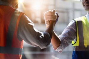 Construction Accident Lawyer in Irvine | Free Consultations 24/7 Two construction workers clasping hands. Seek fair damages for your losses with an Irvine construction accident lawyer.