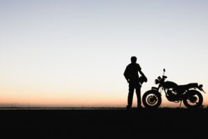 Motorcycle Accident Lawyer in Fullerton | Free Consultations 24/7 Motorcycle rider holds helmet at sunset