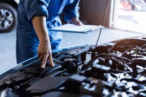 A mechanic looking at a defective car. We can explain what happens if a defective car part caused your accident.