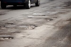 A stretch of road with a lot of potholes. Determine who’s at fault if poor road conditions caused your accident with our legal team.