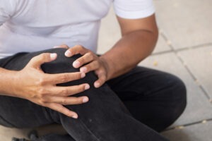 Slip and Fall Accident Lawyer in Chula Vista | Free Consultations 24/7 a man in a white t-shirt and black jeans holding his knee after a slip-and-fall accident
