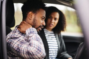 A man holds his neck while the driver looks on after a car accident in Vista, CA. A personal injury attorney can help victims recover damages after a collision.
