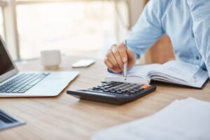Facing Embezzlement Charges in California - What to Expect A businessman with a laptop and a calculator, facing embezzlement charges in California.